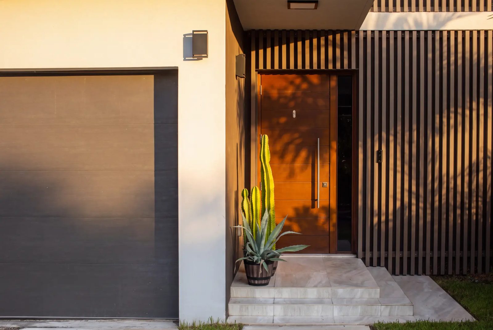 Timber front door in a recessed entry beside a slatted timber screen, lit by low golden sun