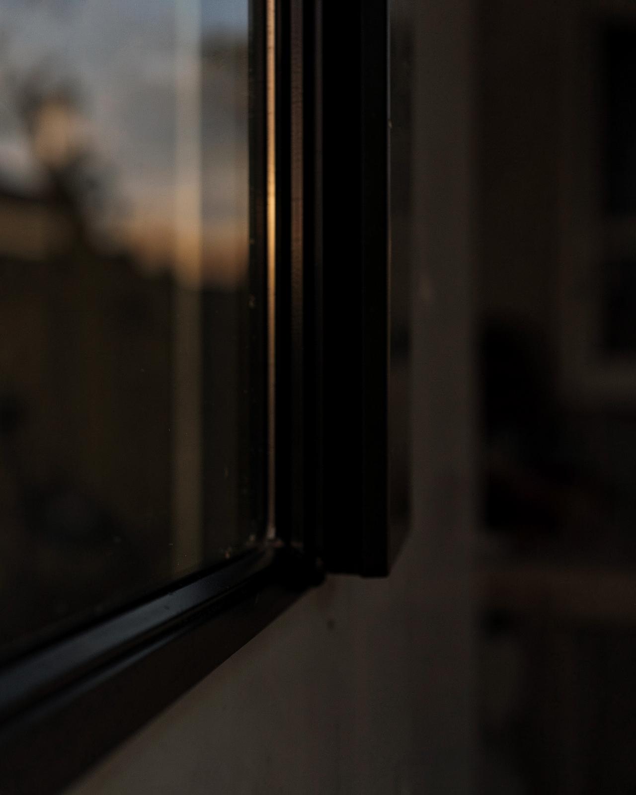 Dark window frame corner reflecting dusk light